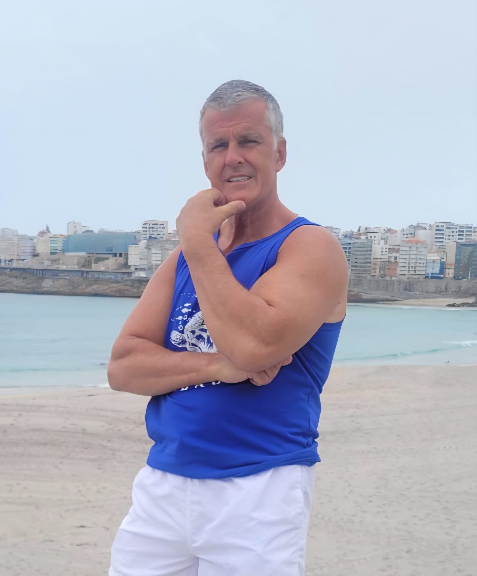 Dominic Pierse standing on a beach wearing a blue T-shirt and white shorts